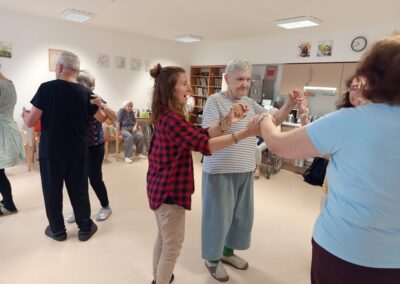 Tanec ve dvojicích: lektorka a senioři se drží za ruce